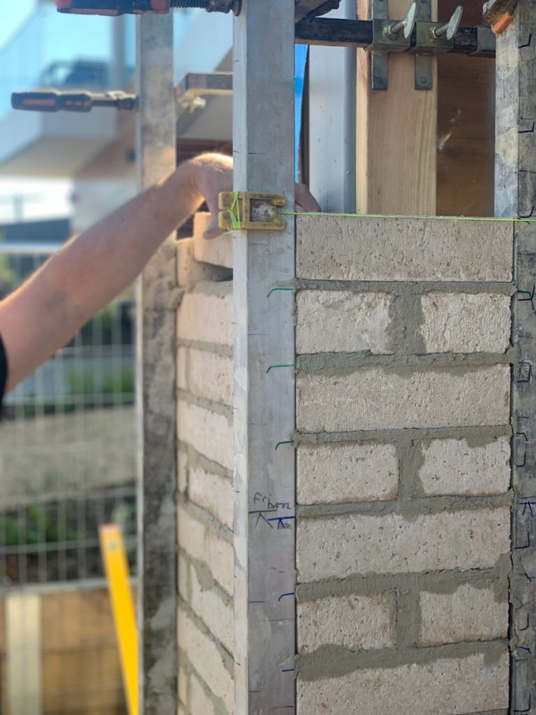 Image is of a bricklayer in Brisbane laying a front brick fence